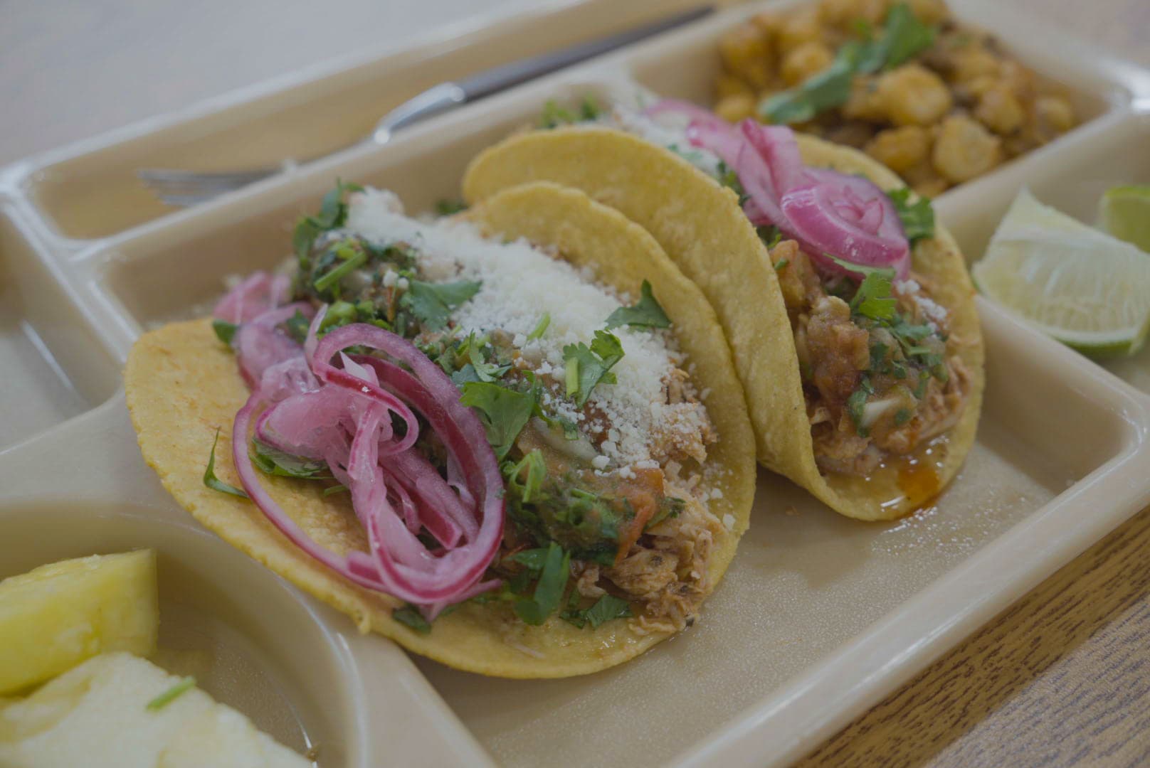 Chicken Rojo tacos topped with pickled red onion, herbs and crumbled cheese.